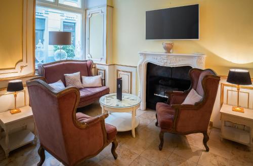 a living room with two chairs and a fireplace at Schlosshotel Römischer Kaiser in Vienna