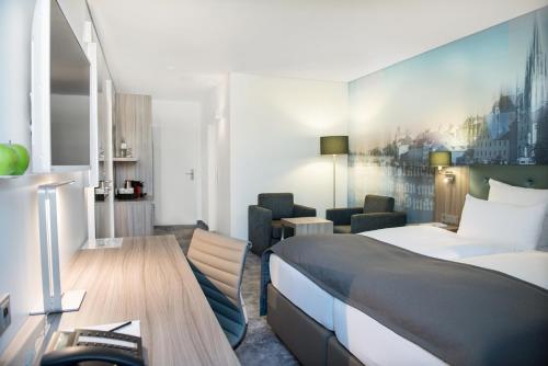 a hotel room with a bed and a desk at Atrium im Park Hotel Regensburg in Regensburg