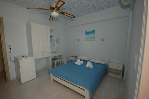 a bedroom with a blue bed and a ceiling fan at Pension Ocean View in Naxos Chora
