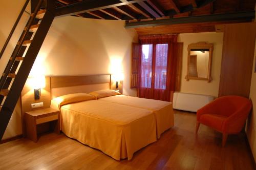 a bedroom with a bed and a ladder and a chair at La Casa del Cubón in Aguilafuente