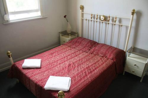 a bedroom with a red bed with two towels on it at The Eastern Hotel Accommodation in Ballarat