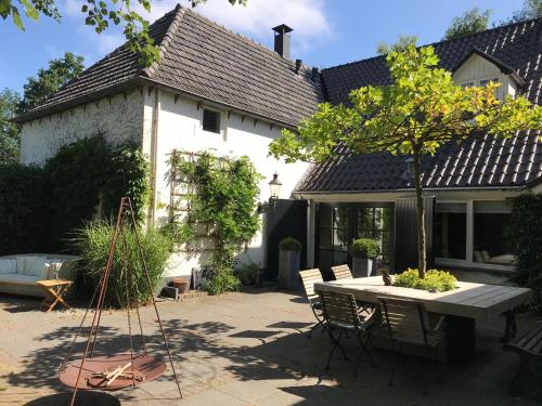 una casa con una mesa y sillas en el patio en B&B Het Wellnest, en Hulshorst