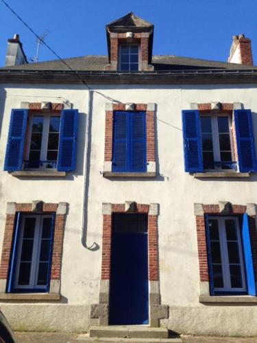- un bâtiment blanc avec des fenêtres bleues et une porte dans l'établissement Maison des remparts, à Guérande
