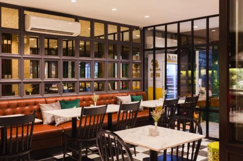 a restaurant with tables and chairs and a bench at Oriental Heritage Hotel in Bangkok