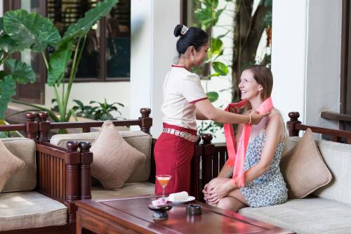 a woman standing next to a woman sitting on a couch at Angkor Palace Suite & Villa in Siem Reap