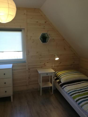 a bedroom with a bed and a desk and a window at Domki Letniskowe Gris in Grzybowo
