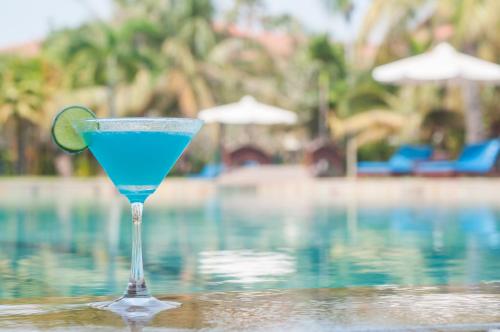 a blue drink sitting on a table next to a swimming pool at Angkor Palace Suite & Villa in Siem Reap