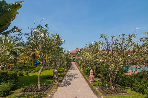 a walkway through a garden with trees and bushes at Angkor Palace Suite & Villa in Siem Reap