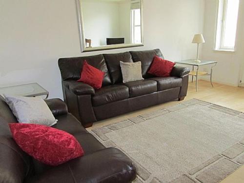 a living room with a brown leather couch with red pillows at Bridge Street Apartments in Inverness