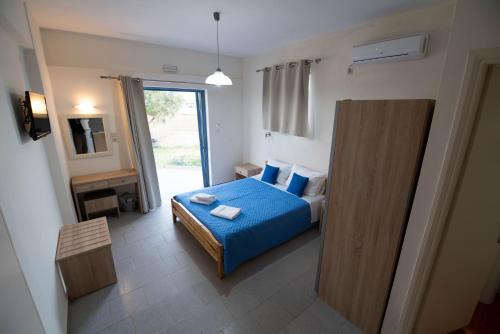 a bedroom with a bed with blue sheets and a window at Electra Studios in Gerani Chanion