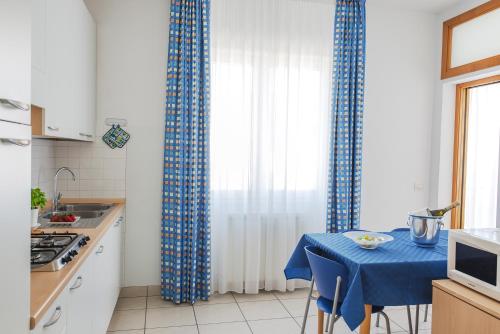 a kitchen with blue curtains and a blue table with chairs at Casa Lucia Centro Apartment Deluxe in Sottomarina