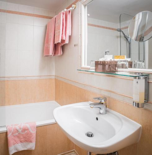 a bathroom with a sink and a mirror and a tub at Schlosshotel Römischer Kaiser in Vienna