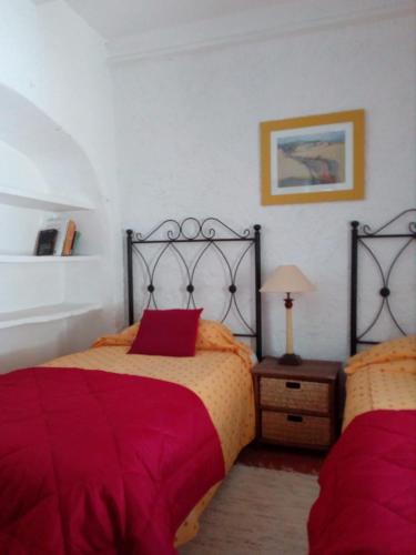 a bedroom with two beds with red sheets at Tranquil Spanish Mountain Retreat in Benirrama