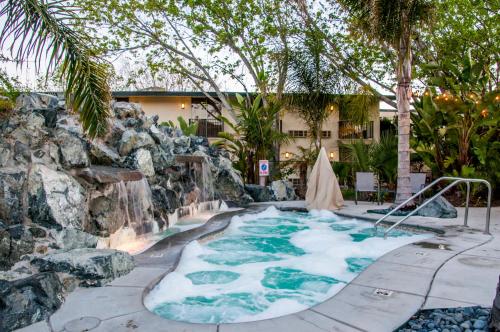 a hot tub with a waterfall in a backyard at Hotel Calle Joaquin - San Luis Obispo in San Luis Obispo