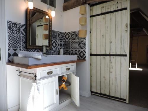 a bathroom with a sink and a mirror and a door at La Closerie Teranga in Bayeux