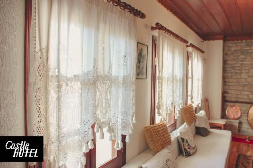 a living room with white curtains and a window at Castle Hotel in Gjirokastër