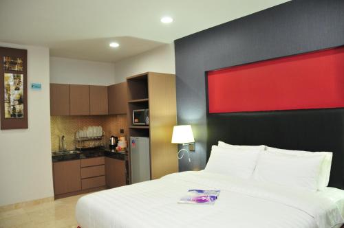 a bedroom with a large bed and a kitchen at The Centro Hotel & Residence By Orchardz in Batam Center