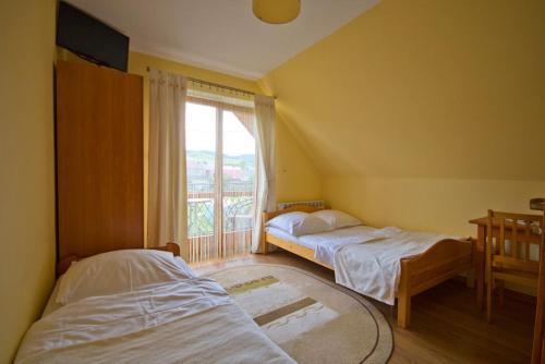 two beds in a room with a window at Wynajem pokoi Natalia in Sromowce Niżne