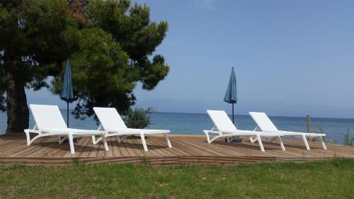 a group of white chairs sitting on a wooden deck near the water at Meli Seaside Villas in Khránoi