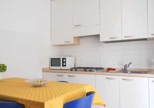 a kitchen with white cabinets and a table with a yellow table cloth at Casa Lucia Centro Apartment Deluxe in Sottomarina