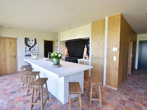 a kitchen with a large white island with wooden stools at Beautiful Holiday Home with Terrace Garden in Diksmuide