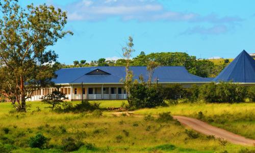 a house with a blue roof in a field at Premier Resort Mpongo Private Game Reserve in Macleantown