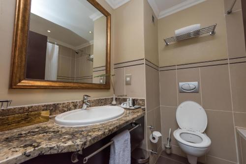 a bathroom with a sink and a toilet and a mirror at Sunbird Capital in Lilongwe