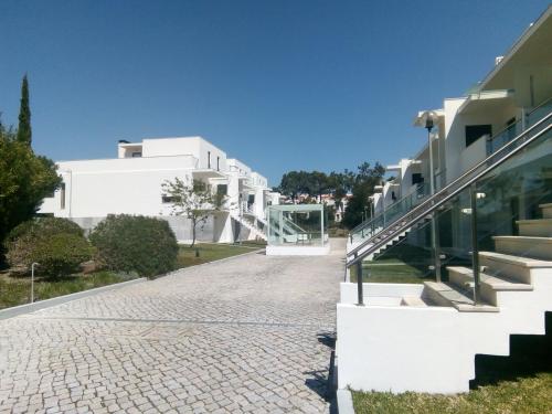 a cobblestone street in front of a white building at Casa das Dunas Soltroia in Troia