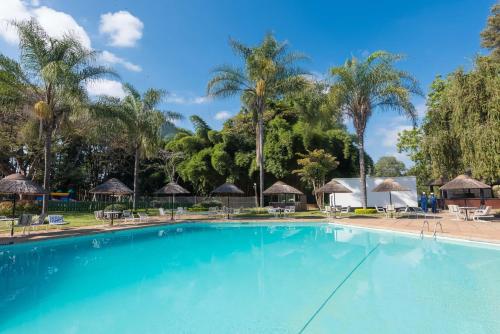 a large swimming pool with palm trees and umbrellas at Sunbird Capital in Lilongwe