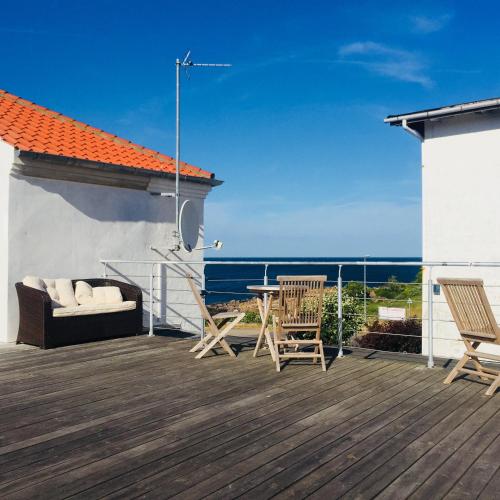 a patio with chairs and a table on a deck at Badepensionat Sandloppen - Ferielejligheder in Allinge