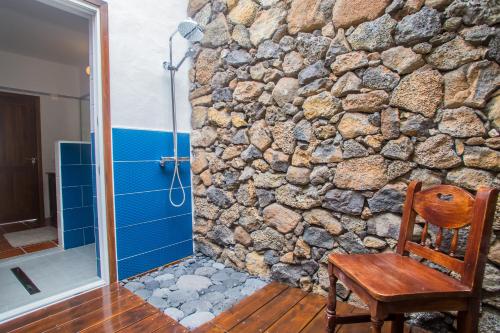a stone bathroom with a shower and a wooden chair at Holiday house Casa Mariposa in Tabayesco in Tabayesco