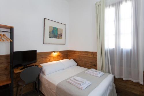 a bedroom with a bed with a desk and a television at Gran H La Marina in Altea
