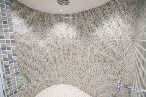 a bathroom with a shower with a tiled wall at The Workshop, Badingham in Badingham