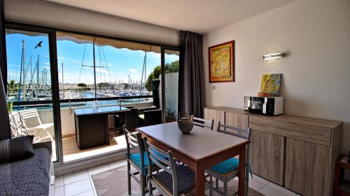 a living room with a table and a view of a marina at Rivages d'Ulysse Port Camargue in Le Grau-du-Roi