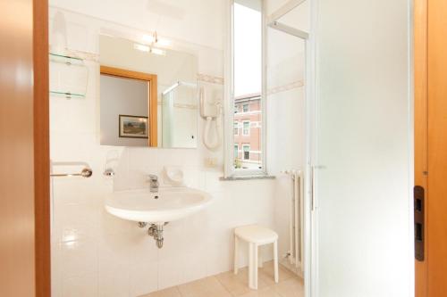 a white bathroom with a sink and a mirror at Albergo Vittoria in Salsomaggiore Terme