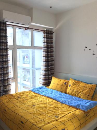 a bedroom with a bed with yellow pillows and a window at Syafiq Suite in Kota Bharu
