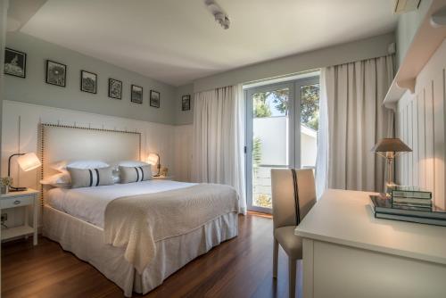 a bedroom with a bed and a window and a desk at Casa Laranja Boutique House in Cascais