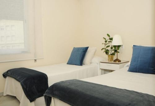 2 camas en una habitación blanca con almohadas azules en Apartamento 2 dormitorios muy centrico, en Jerez de la Frontera