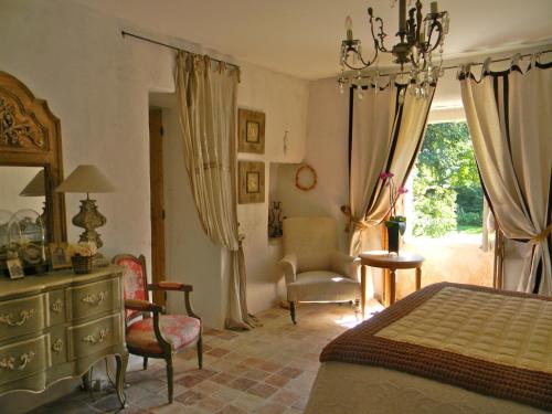 a bedroom with a bed and a chair and a dresser at La Grange à Nicolas in Baume-les-Messieurs