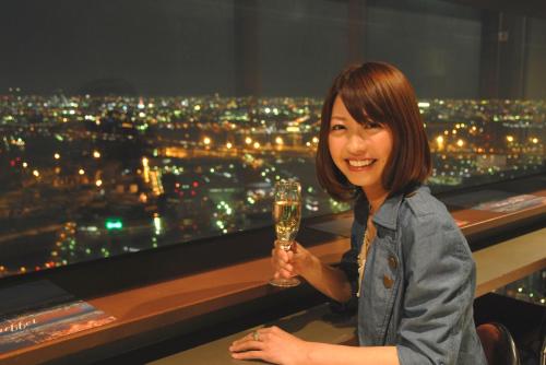 a woman holding a wine glass in front of a city at HOTEL FUKURACIA OSAKA-BAY in Osaka