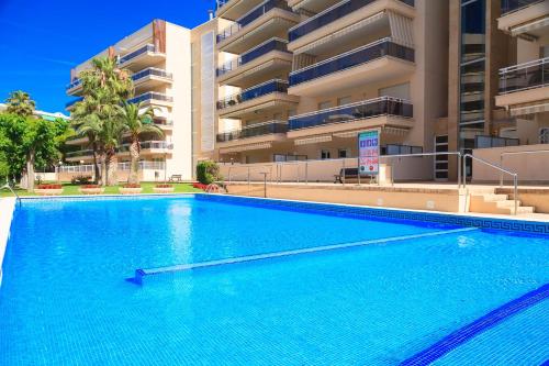 a large blue swimming pool in front of a building at UHC Ventura Park Apartments in Salou