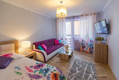 ザコパネにあるLuksusowy Apartament Bon Appetit -Centrum-Krupówki-Zakopaneの紫色のソファとテレビ付きのベッドルーム1室