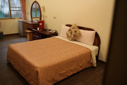 a bedroom with a bed with a dresser and a mirror at Qingxiu Hotel in Baihe