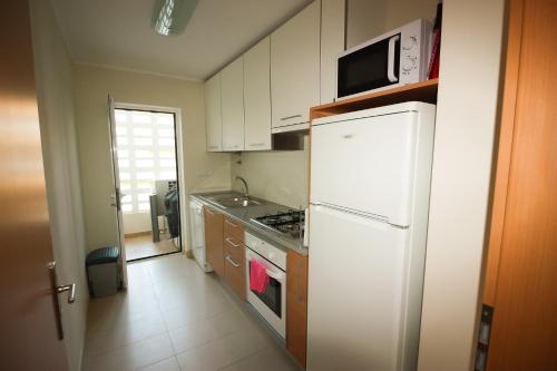 a kitchen with a white refrigerator and a microwave at Franciscos em Cabanas Golf in Conceição