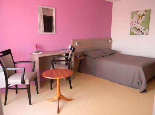 a bedroom with a bed and a desk and a table at Résidence Hôtelière Hélios in Jonzac