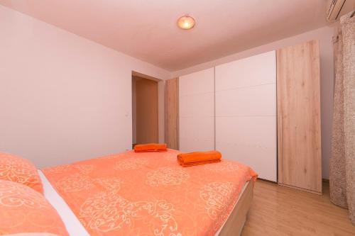 ein Schlafzimmer mit einem Bett mit orangefarbenen Kissen darauf in der Unterkunft Apartment "San Marino" in Baška Voda