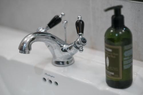 a bottle of soap sitting next to a sink at Saltmarshe Hall in Saltmarshe