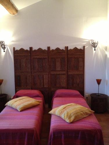 deux lits dans une chambre avec des draps roses dans l'établissement Les Jardins du Rebaut, à Béziers