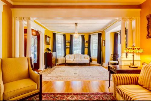 a living room with yellow walls and a couch and a table at 1000 Islands Bed and Breakfast-The Bulloch House in Gananoque