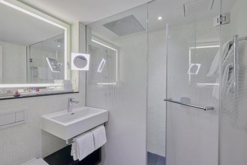 a white bathroom with a sink and a shower at Sorell Hotel Krone in Winterthur